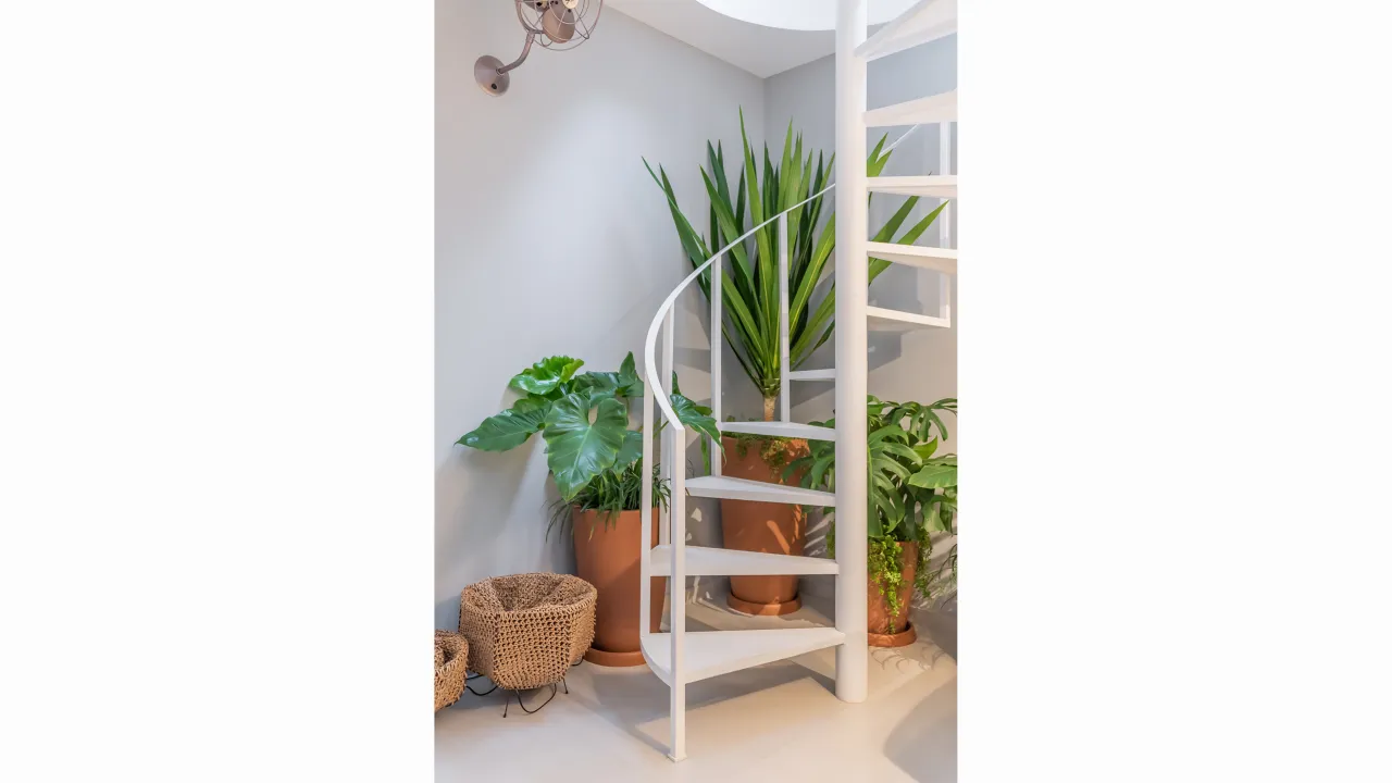 Escada helicoidal branca da Casa Praça com vegetação integrada