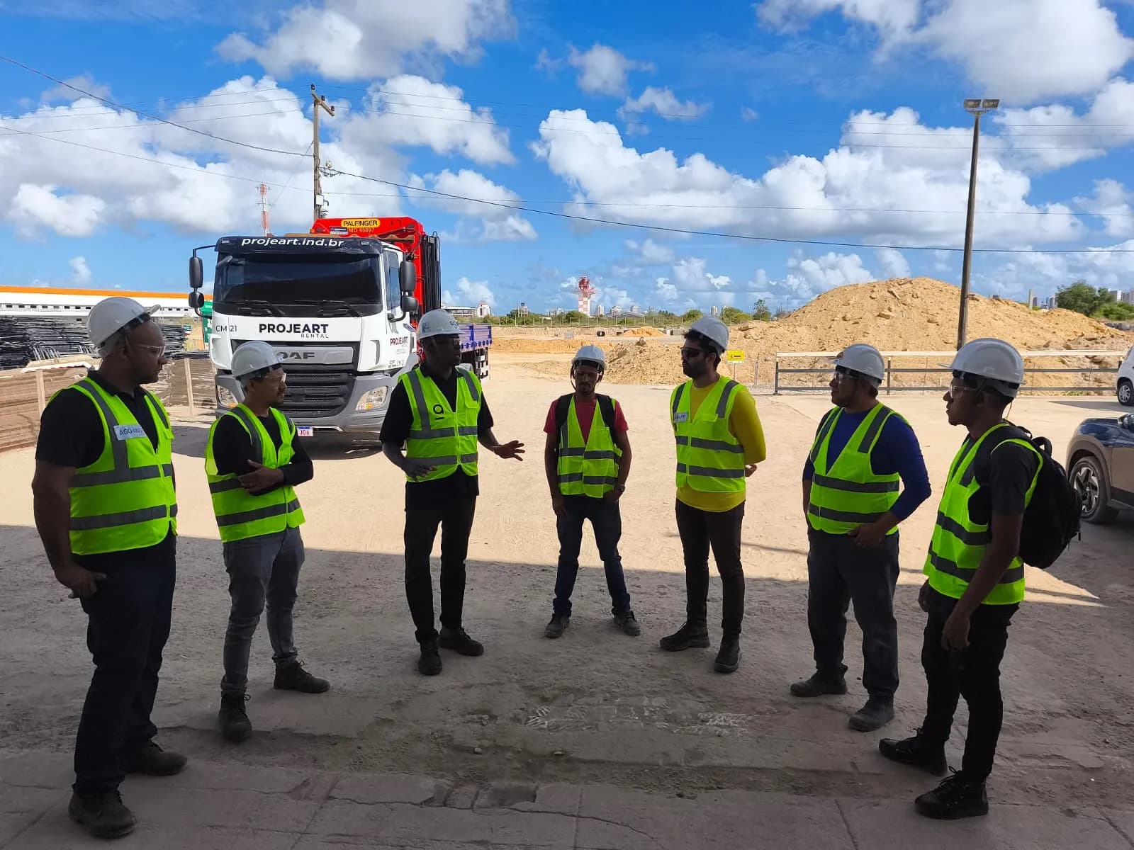 Equipe da Agio reunida em canteiro, de capacete e colete de segurança